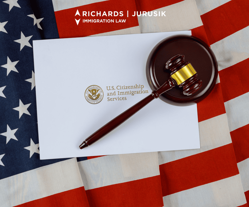 Gavel resting on a USCIS document over an American flag, with Richards Jurusik Immigration Law logo above.